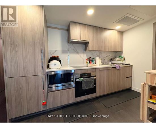 A kitchen with wooden cabinets and a marble backsplash.