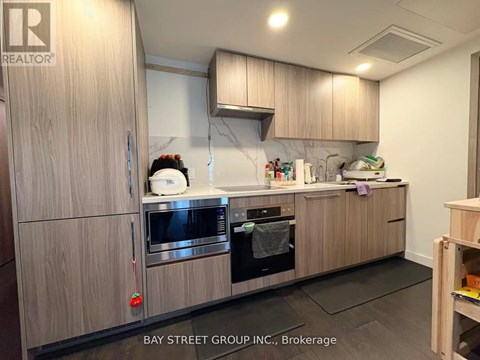 A kitchen with wooden cabinets and a marble backsplash.