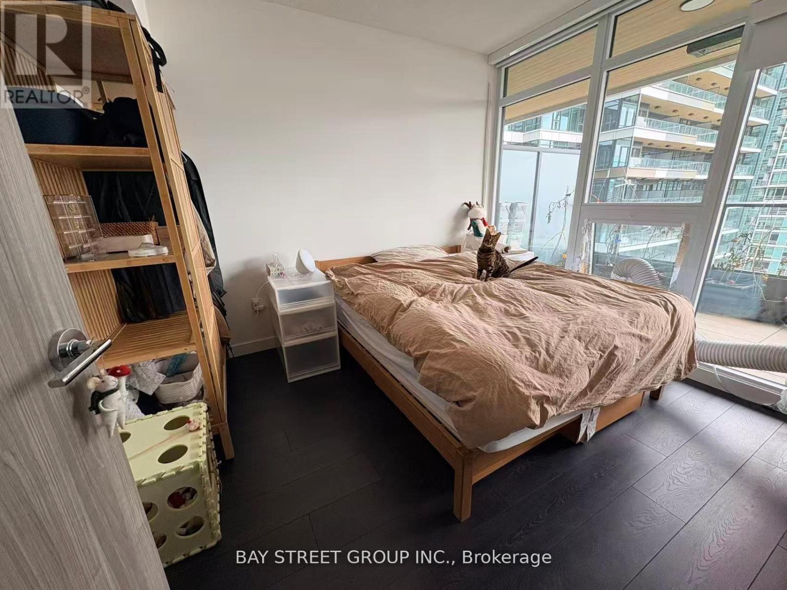 A bedroom with a bed, a window, and a cat on the bed.