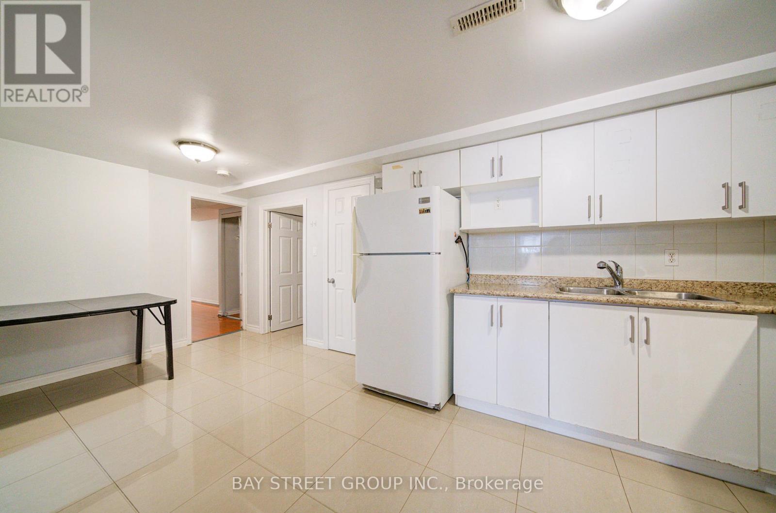 A kitchen with white cabinets and a white refrigerator.