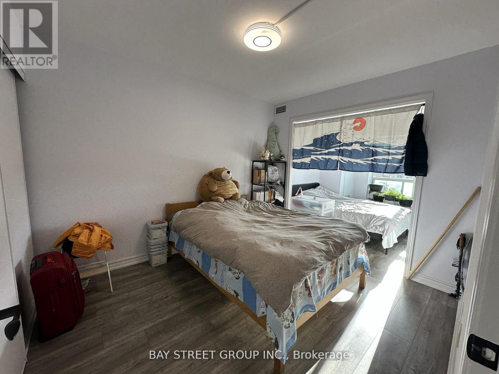 A bedroom with a bed, a chair, and a suitcase.