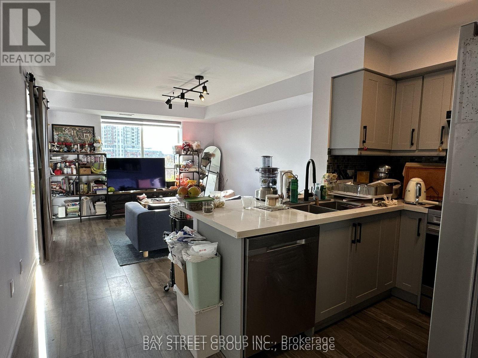 A kitchen with a refrigerator, sink, and a dining table with chairs.
