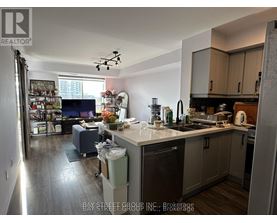 A kitchen with a refrigerator, sink, and a dining table with chairs.