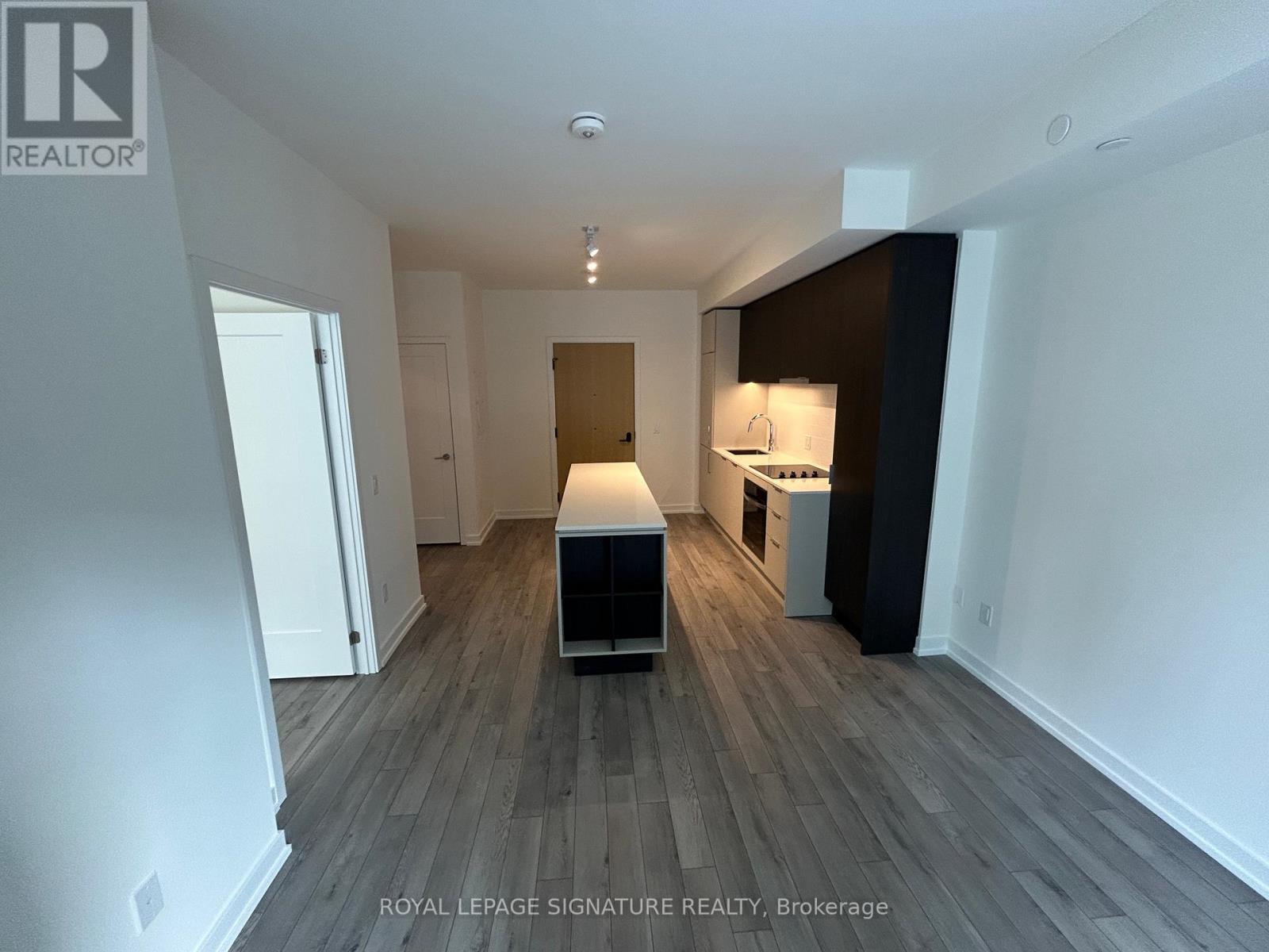 A spacious room with wooden flooring and white walls.