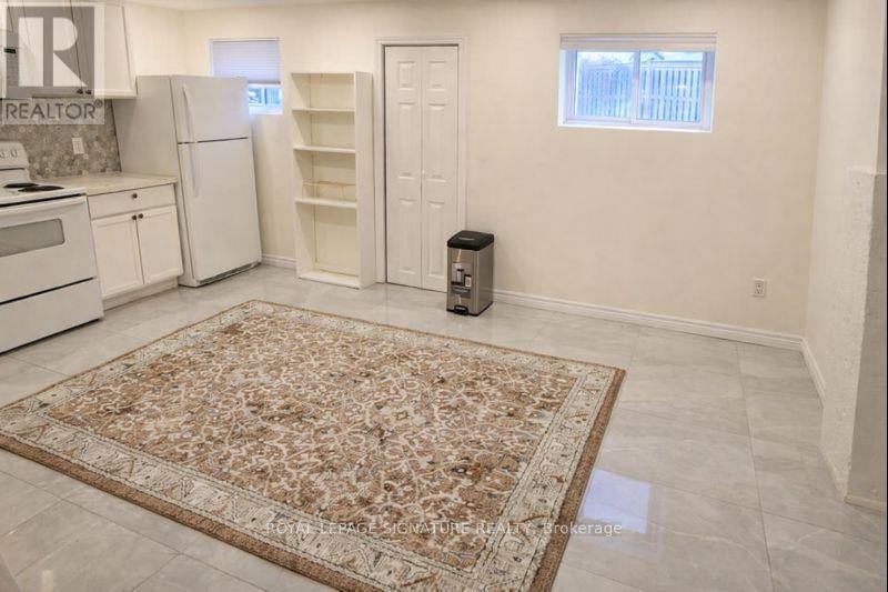 A kitchen with a rug on the floor and a refrigerator with its door open.