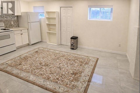 A kitchen with a rug on the floor and a refrigerator with its door open.