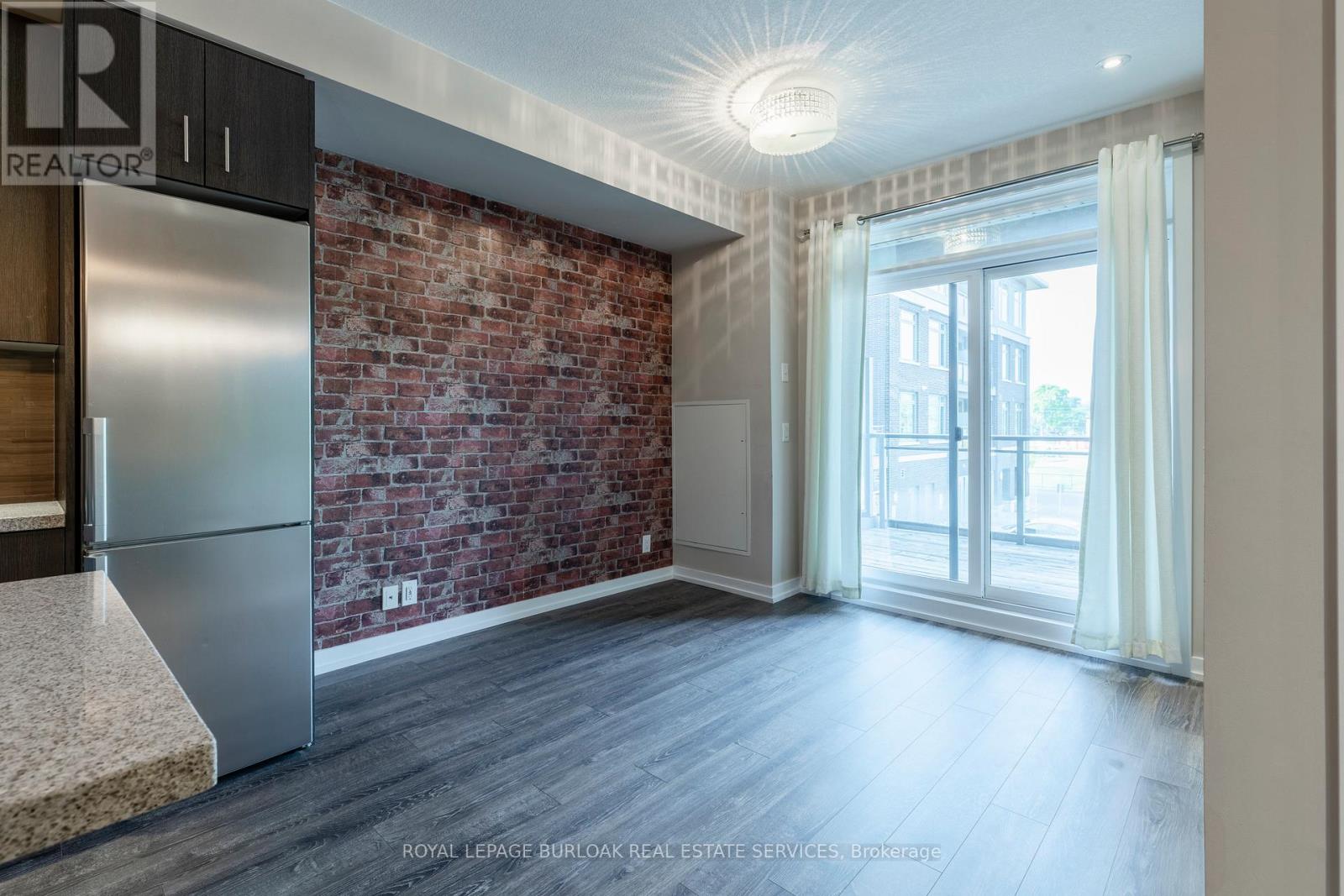 A kitchen with a refrigerator and a brick wall.