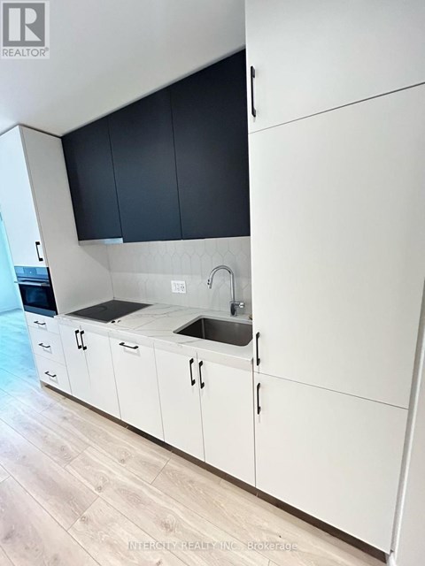 A kitchen with white cabinets and a black countertop.
