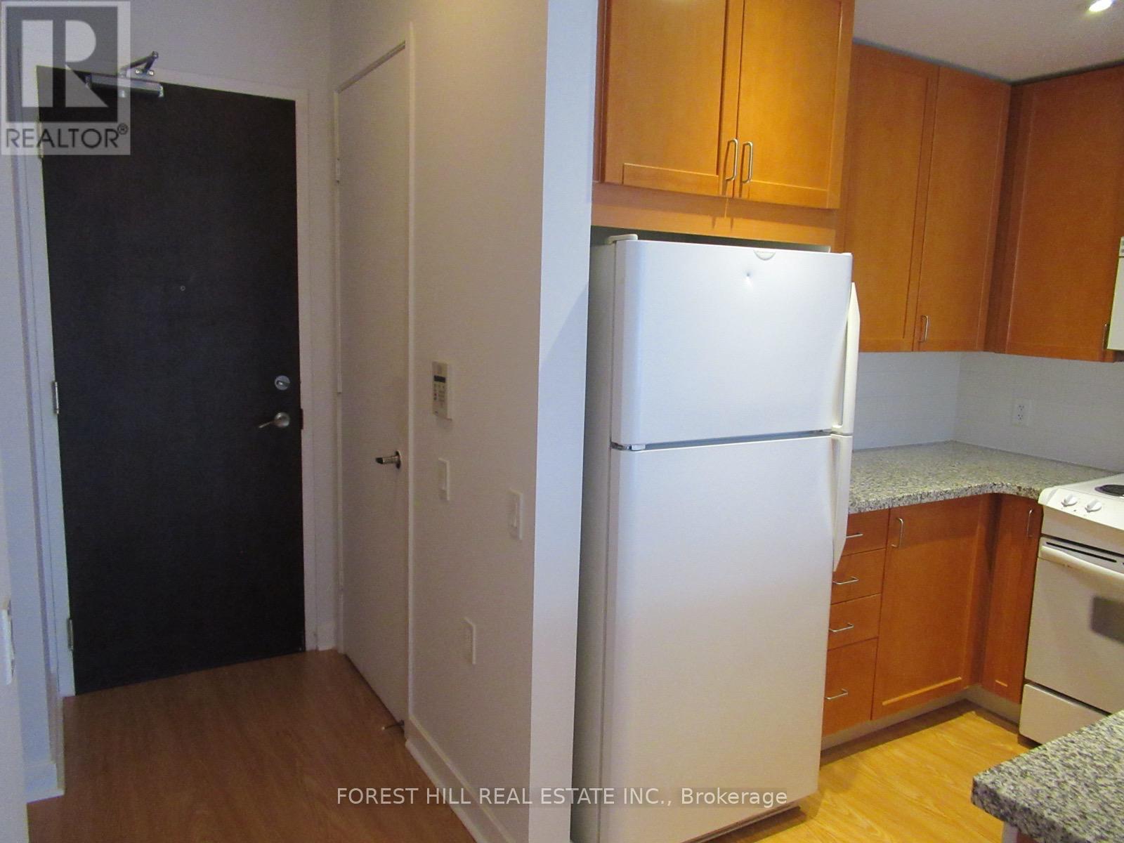 A kitchen with a white fridge and wooden cabinets.