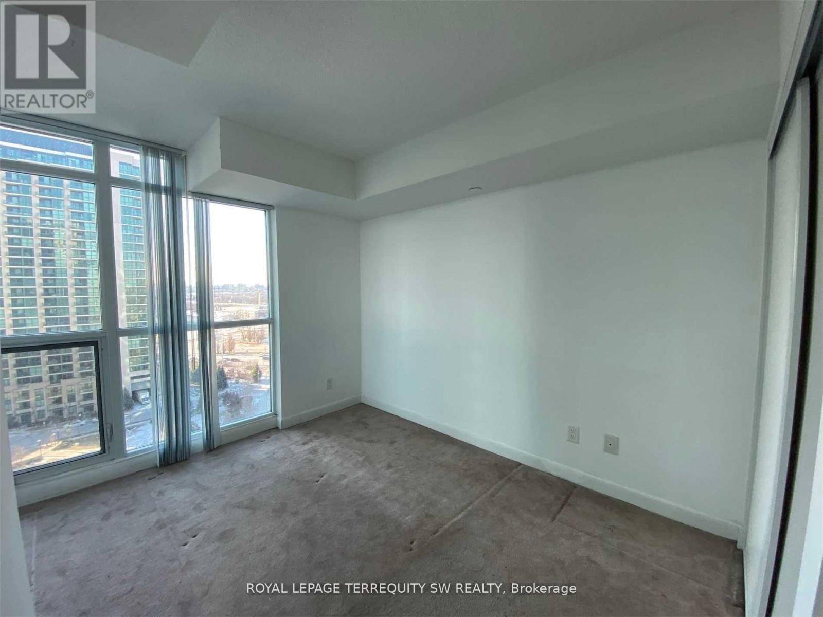 A large empty room with a view of a cityscape through the windows.
