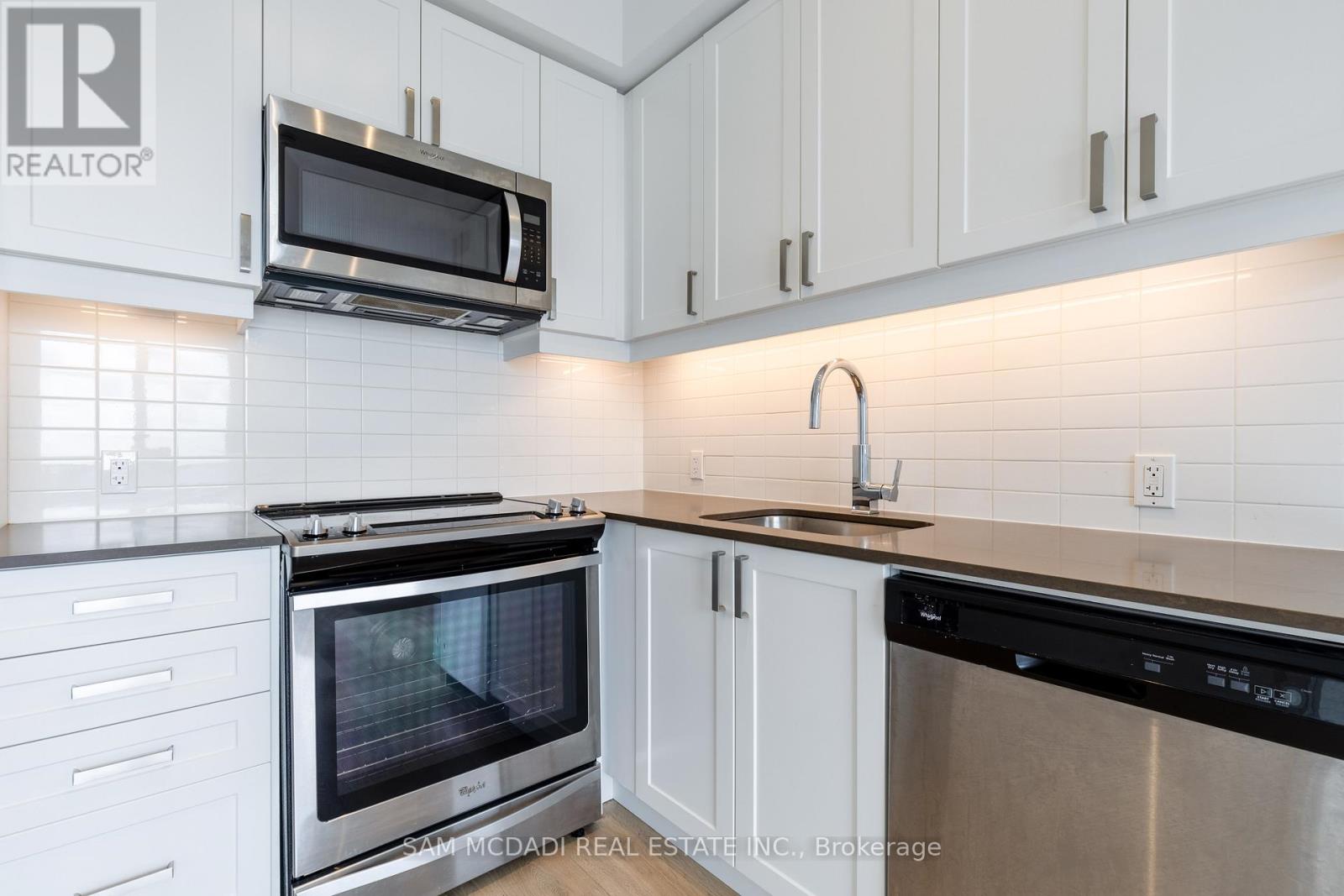 A kitchen with white cabinets and a black dishwasher.