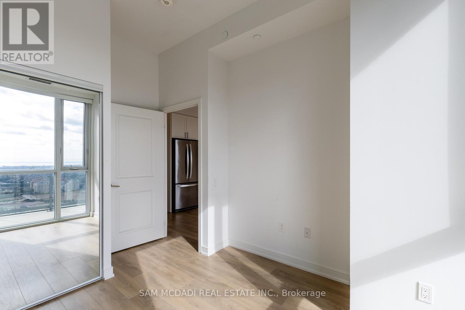 A white room with a door leading to a kitchen area.