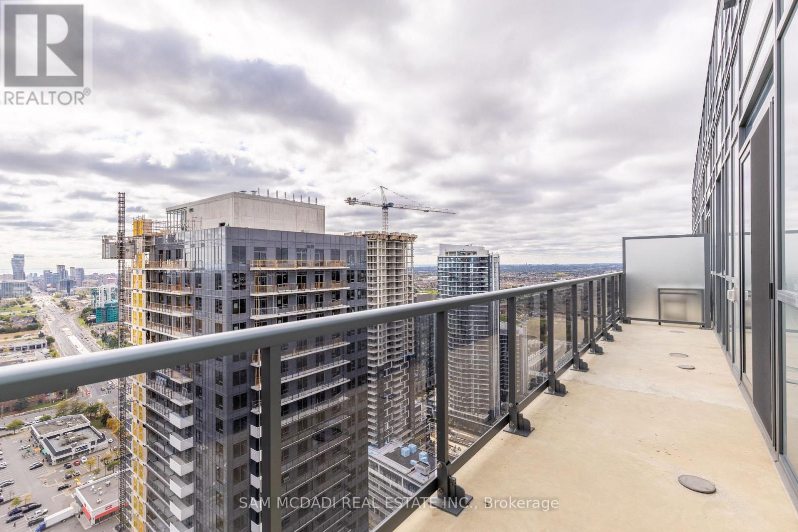 A balcony overlooks a cityscape with a building under construction in the background.