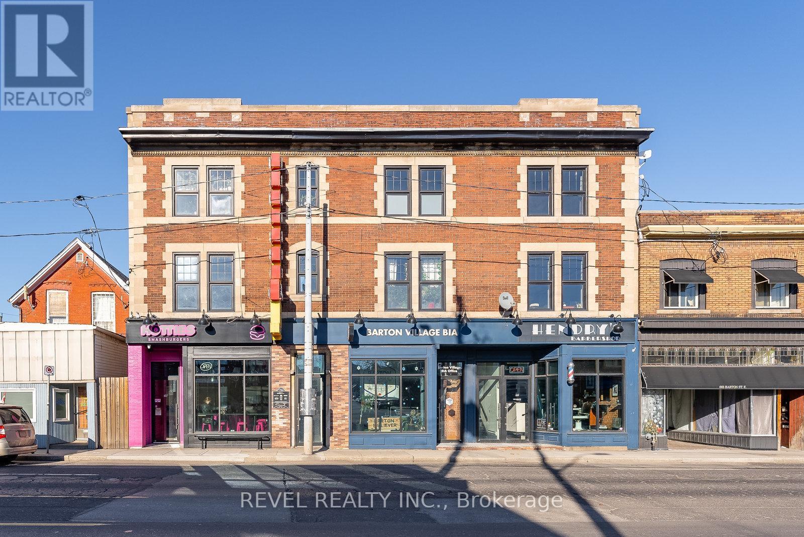 A building with a sign that says "REVEL REALTY INC., Brokerage" in front of it.