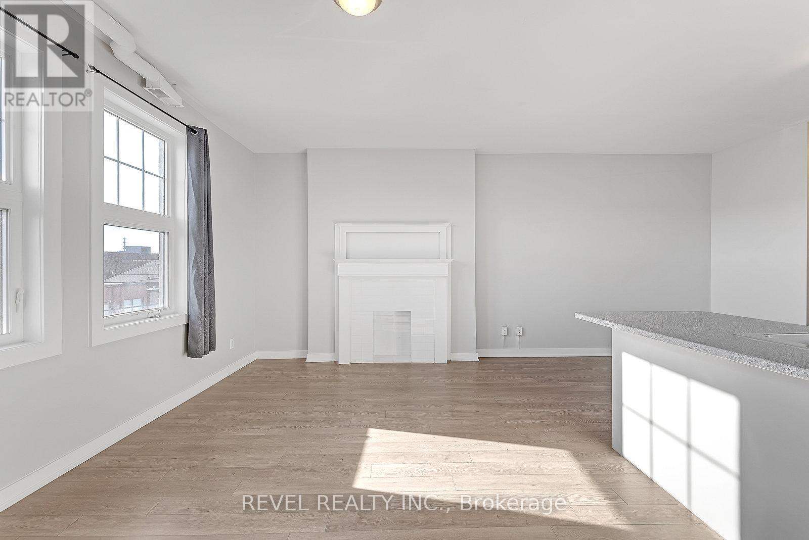 A spacious, empty room with a large window and a fireplace.