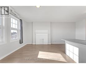 A spacious, empty room with a large window and a fireplace.