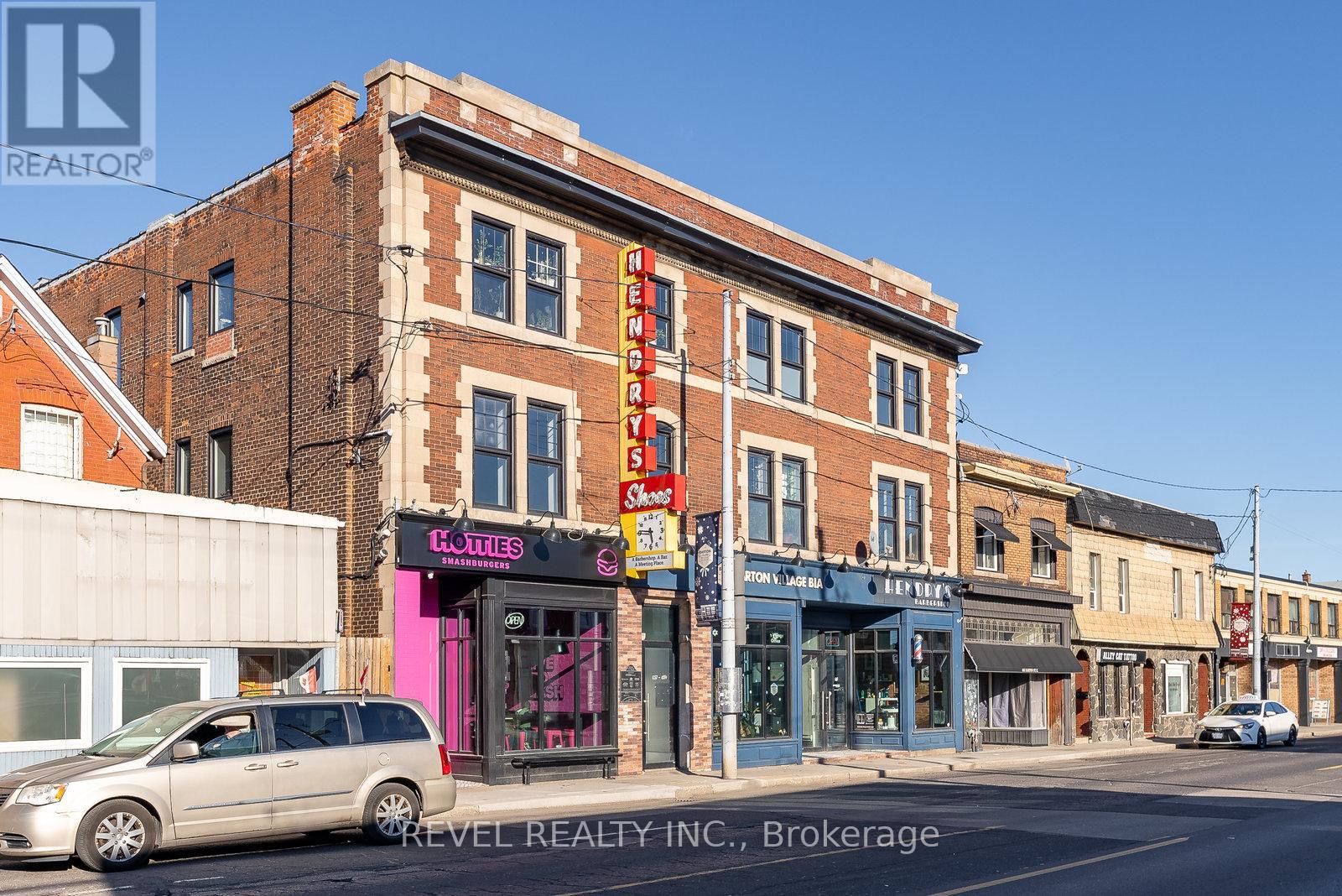 A street view with a building that has a pink sign on it.