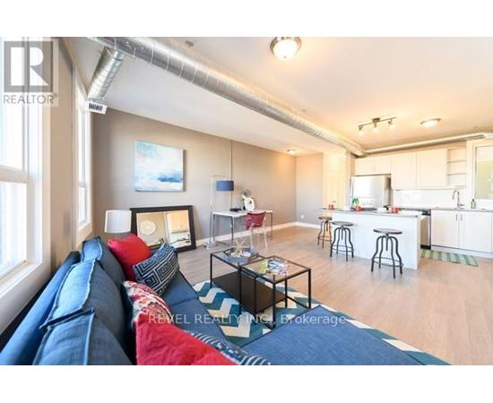 A living room with a blue couch and a kitchen in the background.