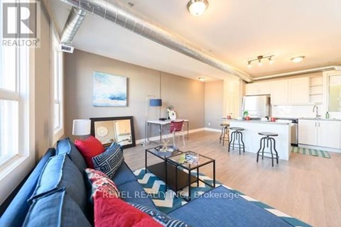 A living room with a blue couch and a kitchen in the background.