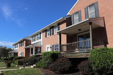 a brick apartment building with a porch and a blue sky