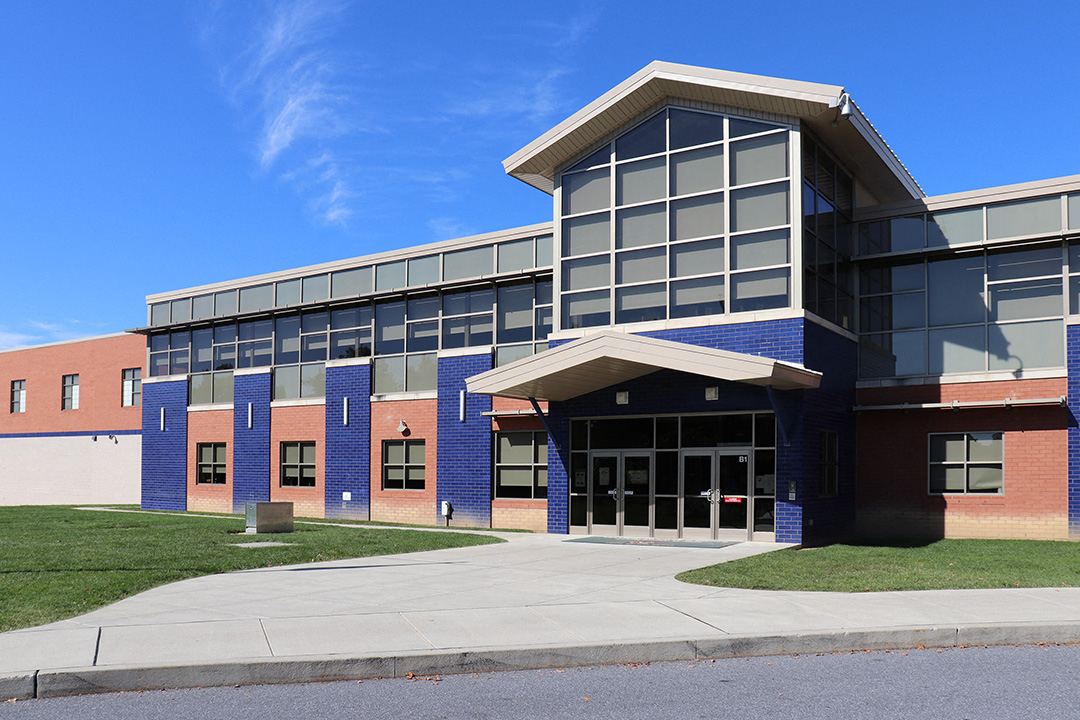 a blue and brick building with a sidewalk and grass
