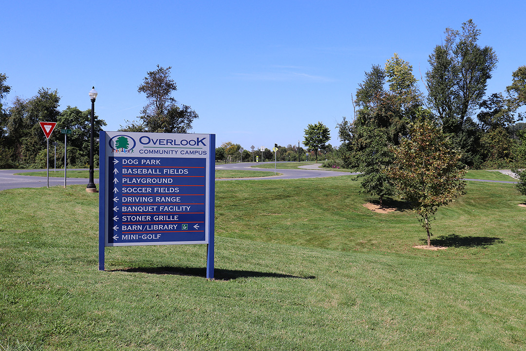 a blue sign in the middle of a park
