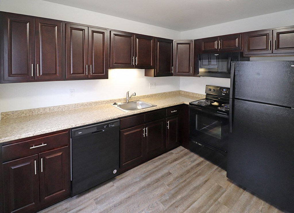 a kitchen with dark wood cabinets and a sink and a refrigerator