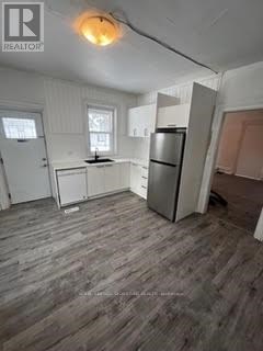 A kitchen with a refrigerator, sink, and cabinets.