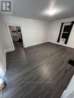A room with wooden flooring and a window with black blinds.