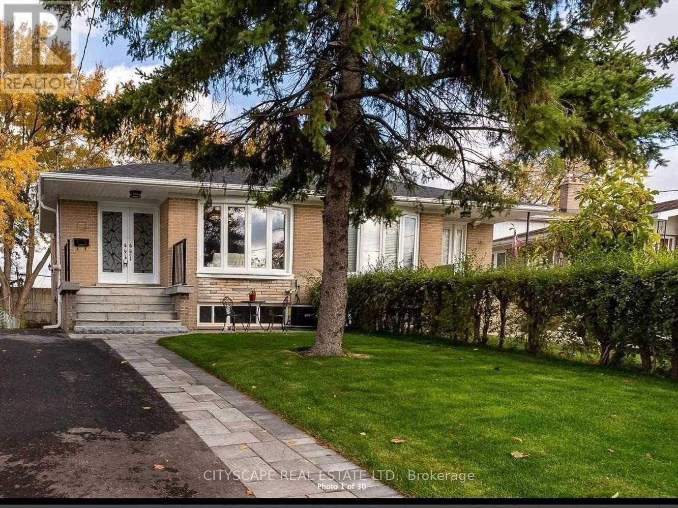 A house with a front yard and a tree in front of it.