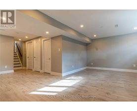 A spacious room with wooden flooring and a staircase leading to another level.