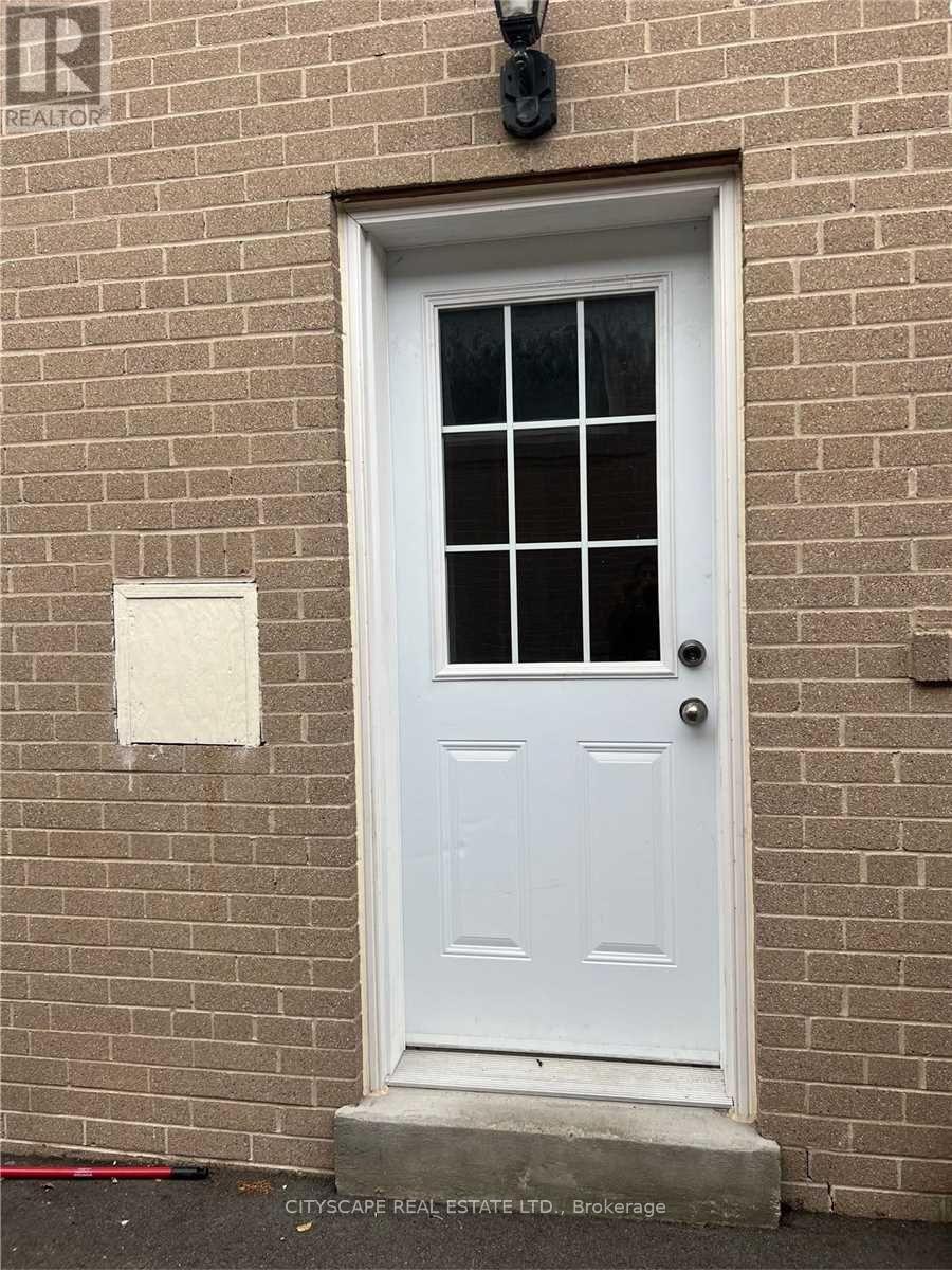 A white door with a glass window is set in a brick wall.