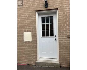 A white door with a glass window is set in a brick wall.