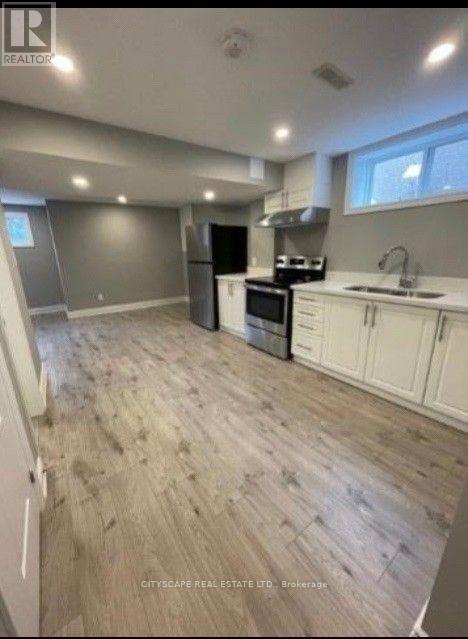 A kitchen with white cabinets and a wooden floor.