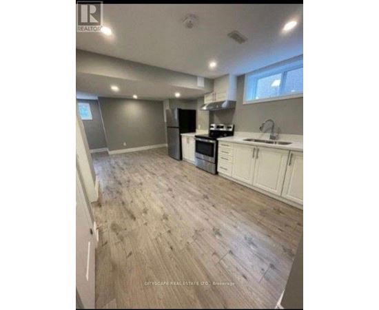 A kitchen with white cabinets and a wooden floor.