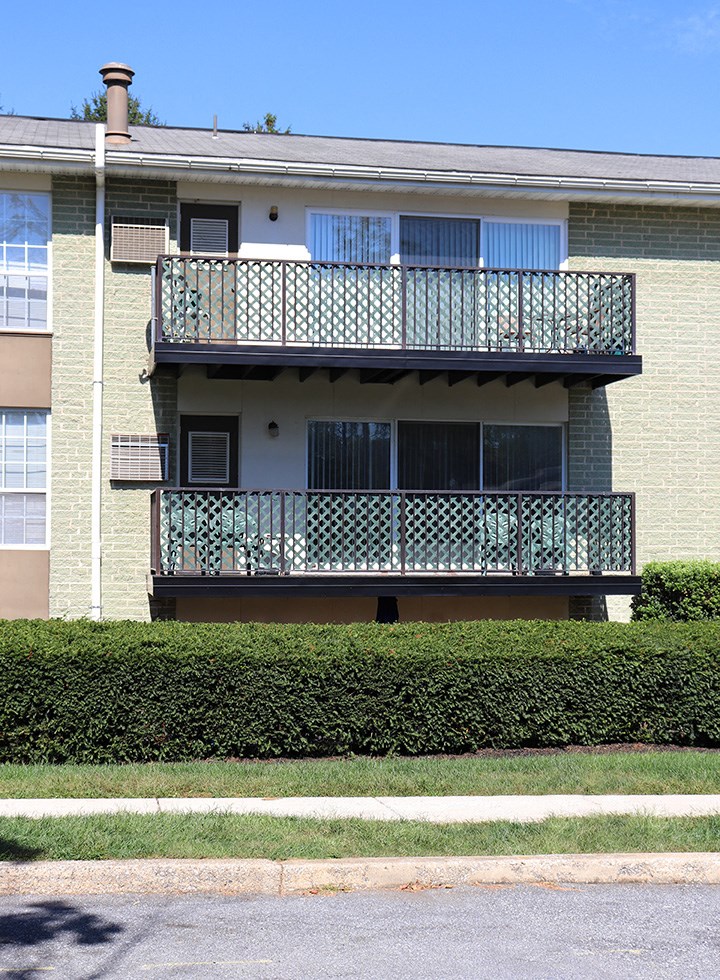 an apartment building with two balconies and a sidewalk