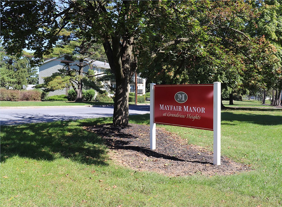 a sign sitting in the grass next to a tree