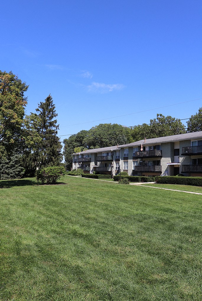 a row of apartment buildings on a green lawn