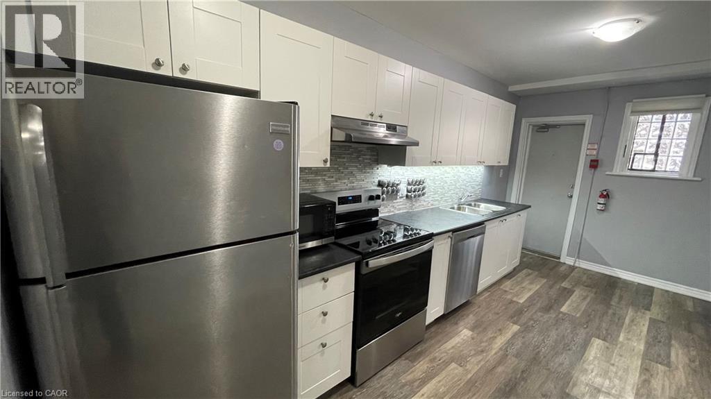 A modern kitchen with a stainless steel refrigerator and wooden flooring.