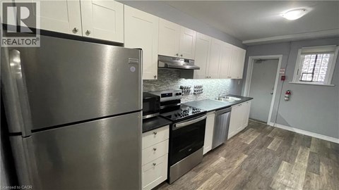 A modern kitchen with a stainless steel refrigerator and wooden flooring.