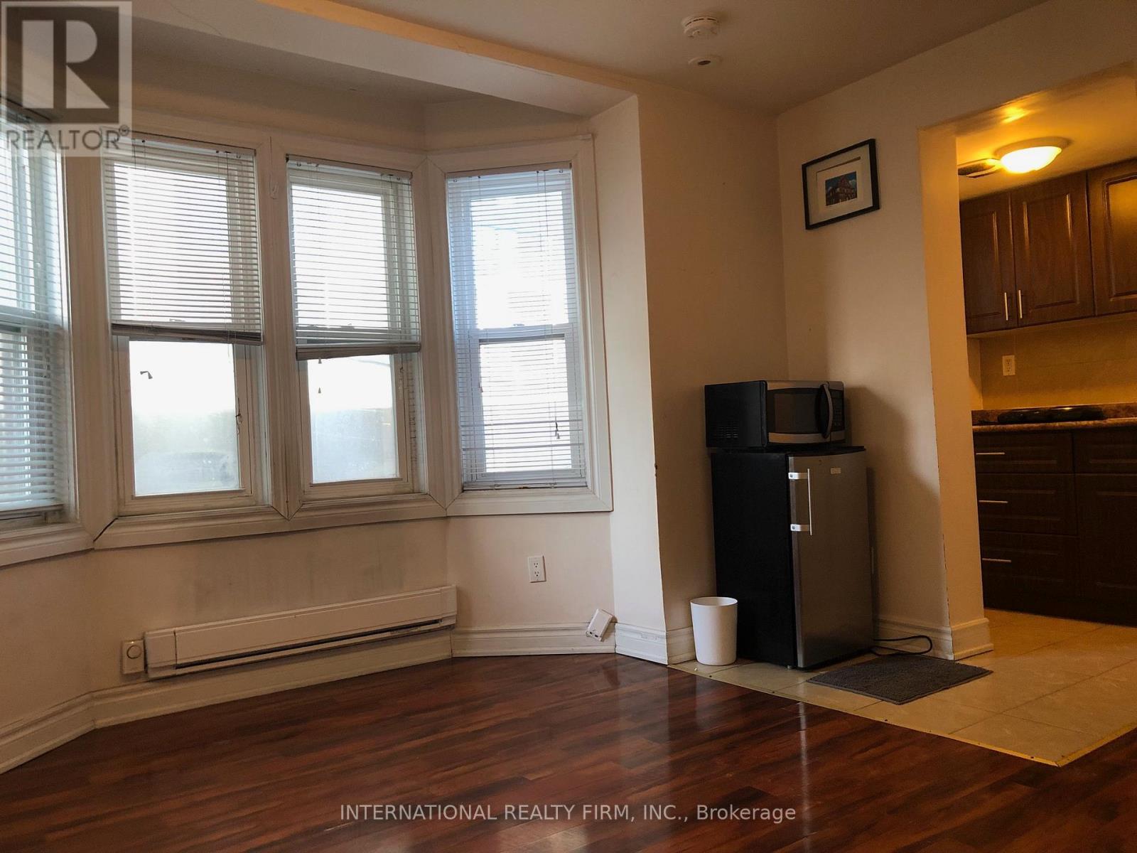 A room with a window, a fridge, and a cabinet.