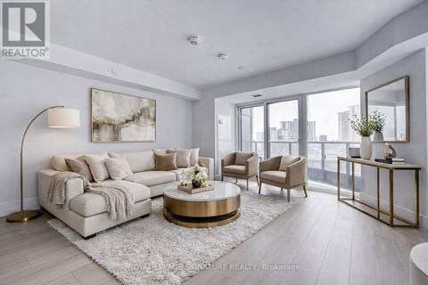 A living room with a large couch, a coffee table, and a painting on the wall.