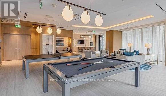 A billiard table is in the middle of a well-lit room with a pool table and a couch.