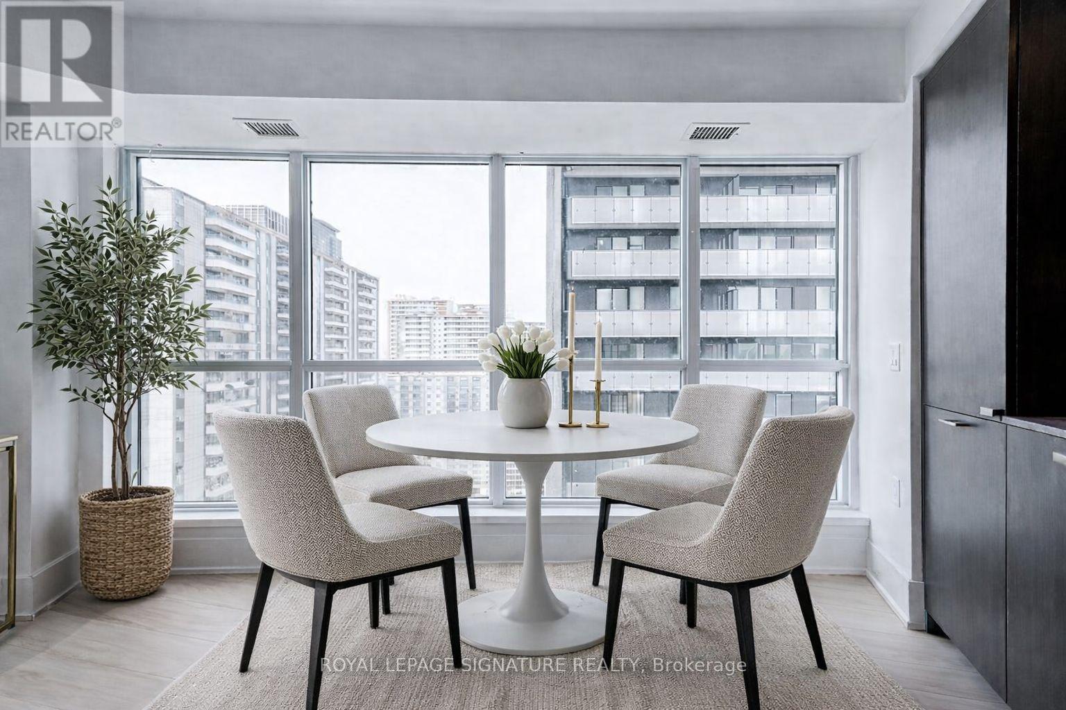 A dining room with a table and chairs in front of a large window.