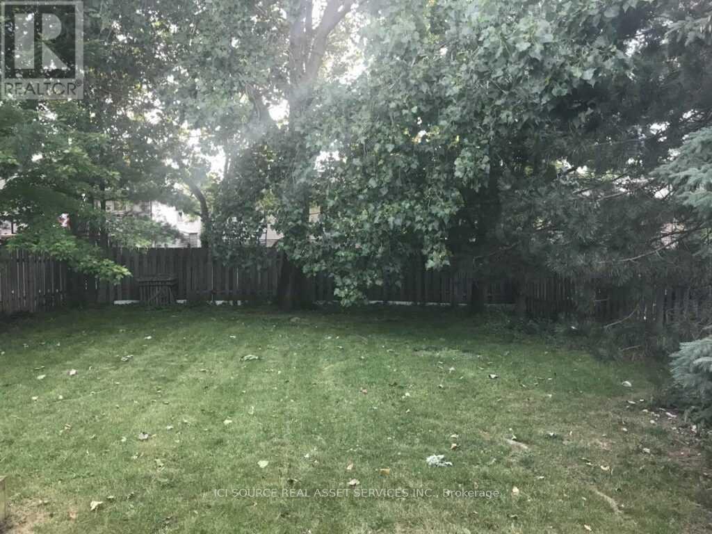 A backyard with a wooden fence and trees.