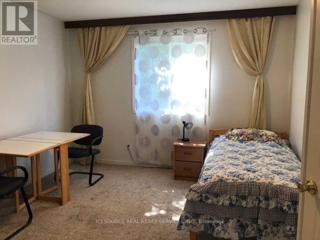 A bedroom with a bed, desk, chair, and window with curtains.