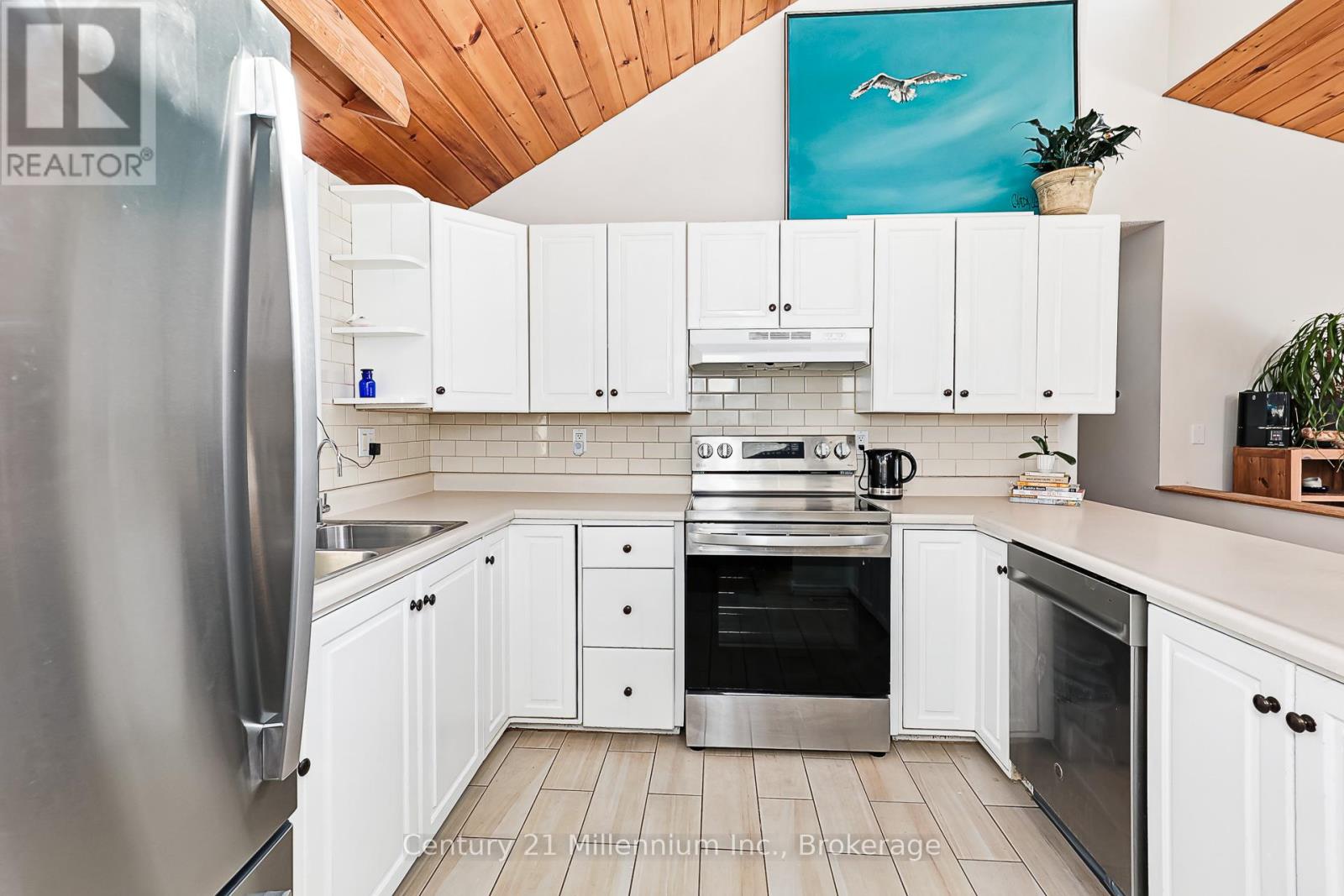 A kitchen with white cabinets and a wooden ceiling.