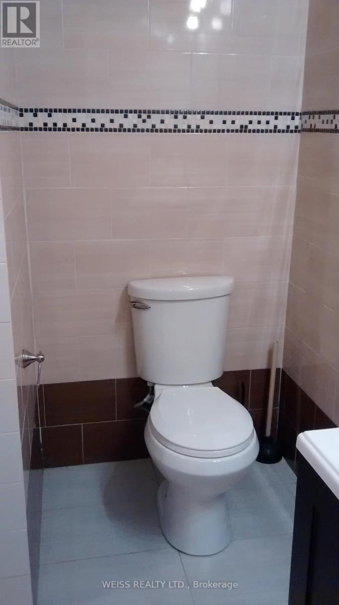 A white toilet in a bathroom with a tiled wall.