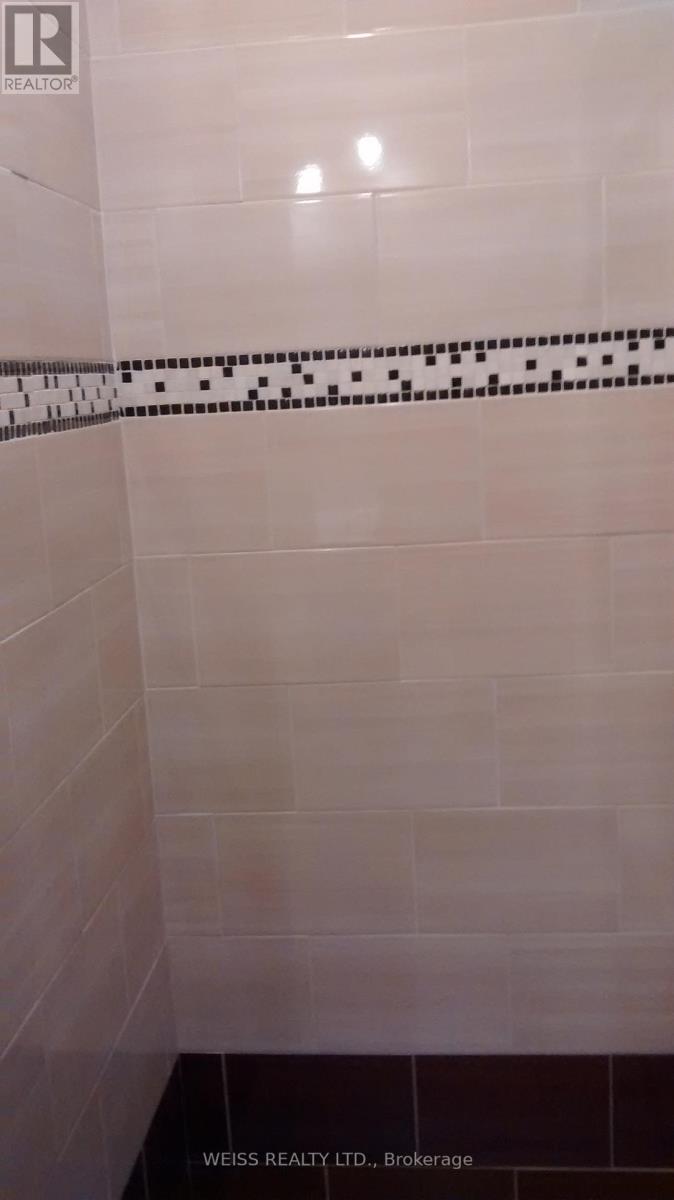A white tiled shower with a black and white tile border.