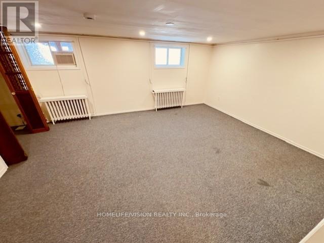 A spacious room with a carpeted floor, a window, and a door.